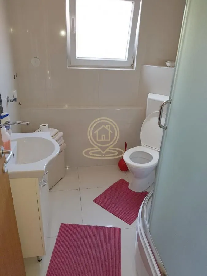 Kupatilo opremljeno umivaonikom, WC šoljom i tuš kabinom.