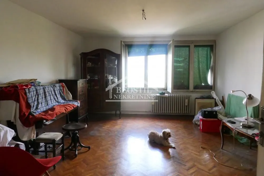Dnevna soba sa drvenim parketom, nameštajem i prozorom.