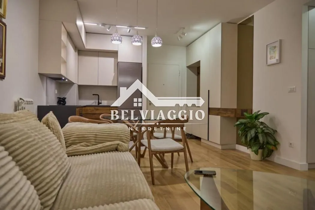 Living room with a sofa, dining area, and fitted kitchen in the background.