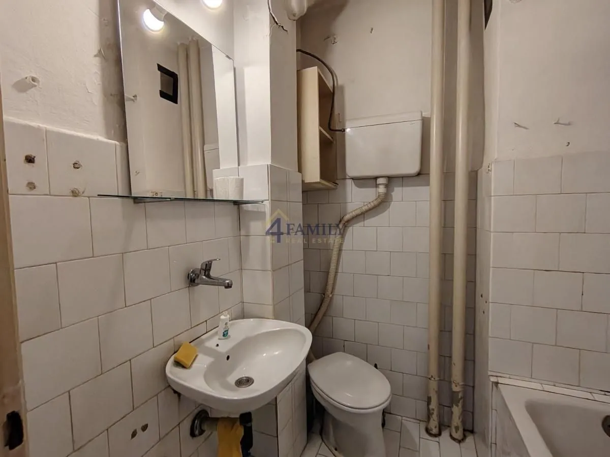 Manje kupatilo sa sanitarijama i belim pločicama.