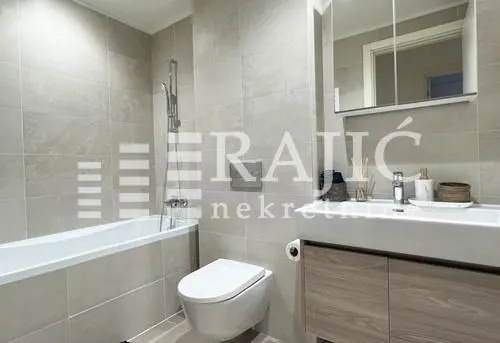 Modernly equipped bathroom with a bathtub, toilet, and washbasin.
