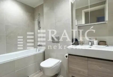 Modernly equipped bathroom with a bathtub, toilet, and washbasin. - image 9
