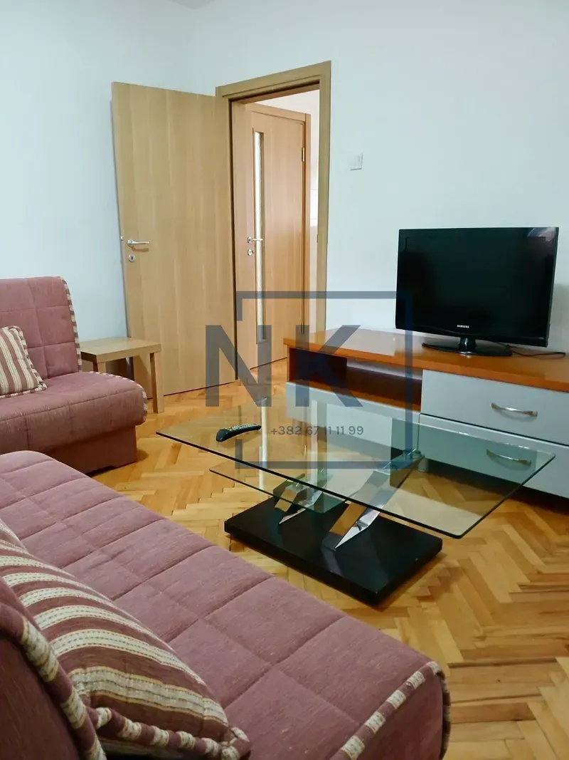 Living room with sofa set, TV unit, and a glass coffee table.