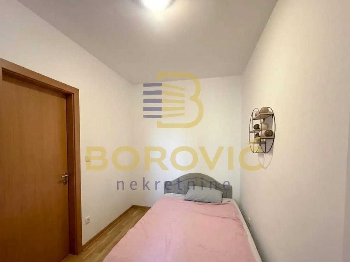 Manja spavaća soba sa krevetom i drvenim vratima.