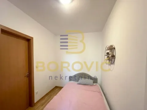 Manja spavaća soba sa krevetom i drvenim vratima. - image 8