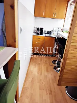 Small wooden kitchen with a bar table and chairs. - image 6