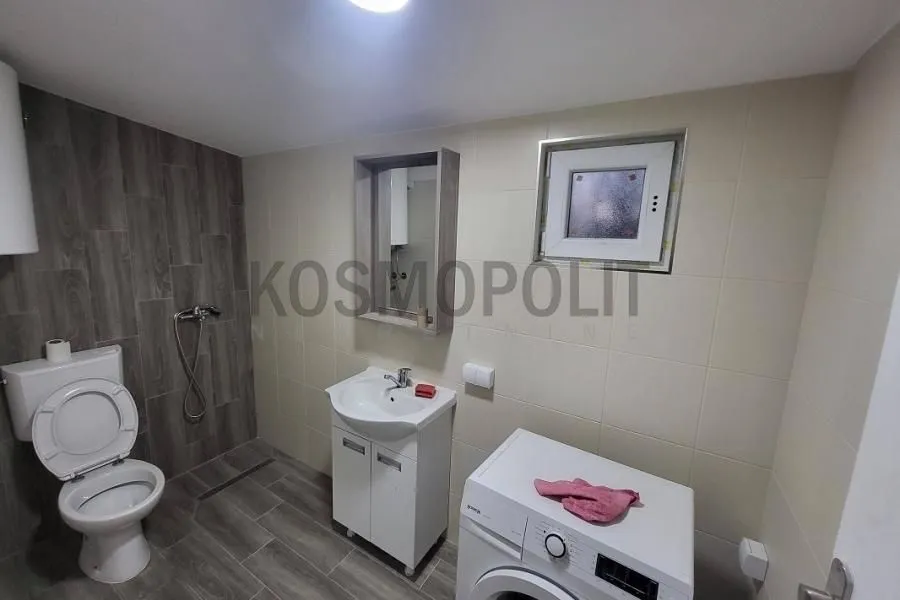 Bathroom equipped with sanitary fixtures, a sink, a mirror, and a washing machine.