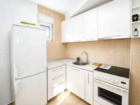 Manja svijetla kuhinja sa bijelim elementima i šporetom. - image 3