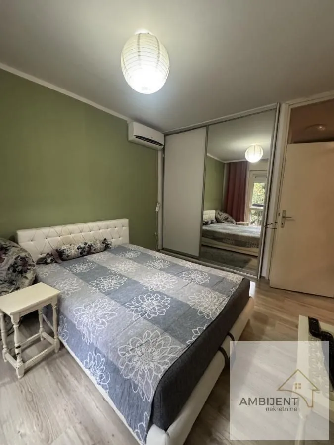 Spavaća soba sa bračnim krevetom i ugradnim ormanom sa ogledalom.