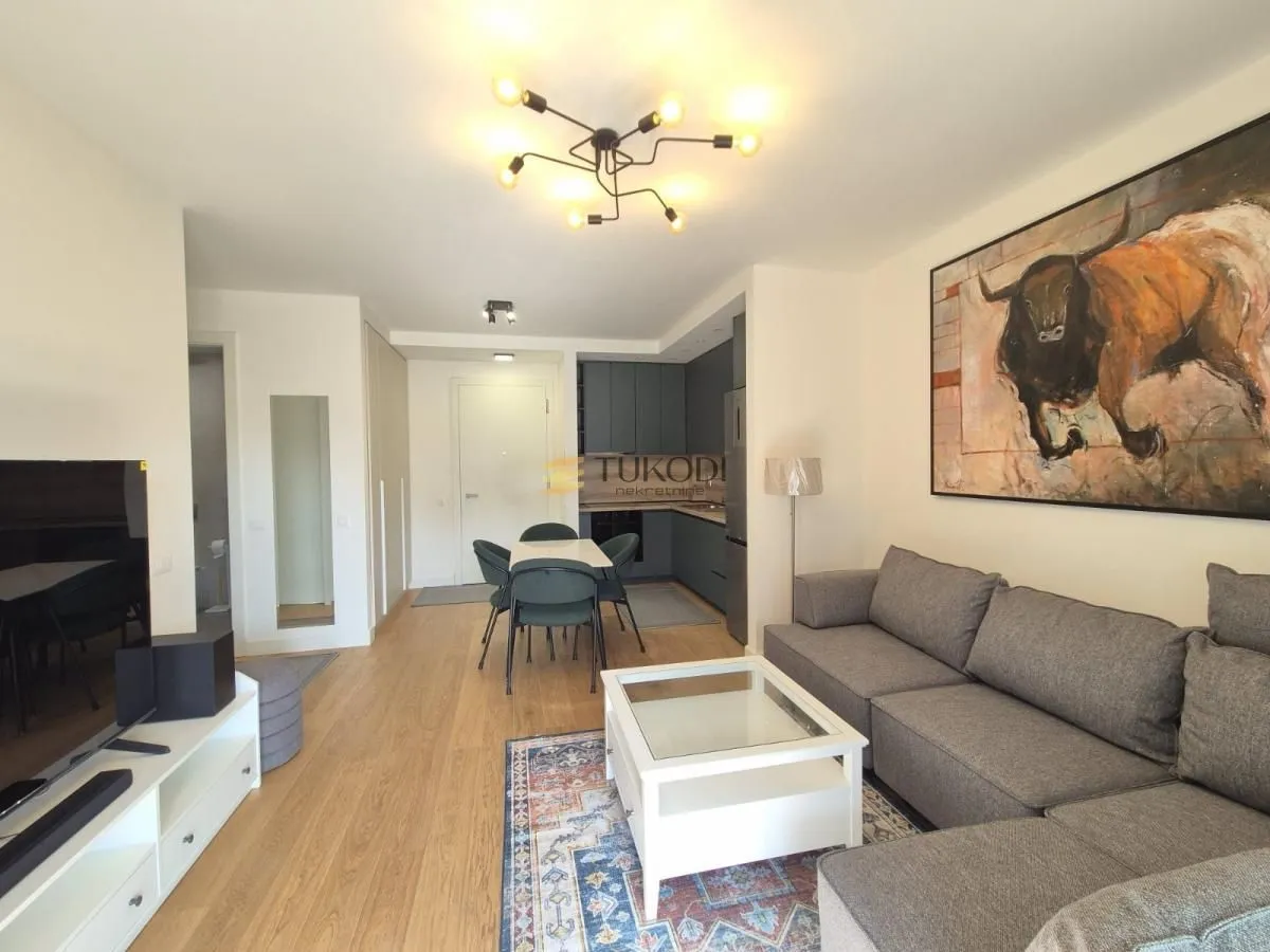 Living room with a sofa and a dining area in the background.