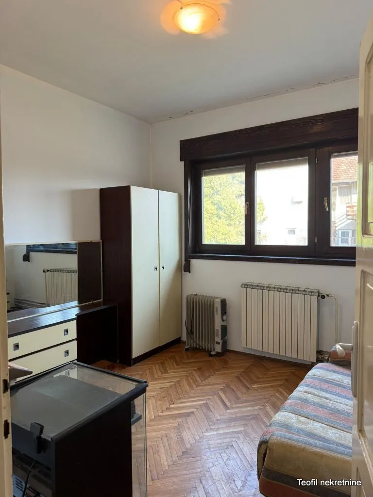 Nameštena spavaća soba sa ormarom, krevetom i prozorom.