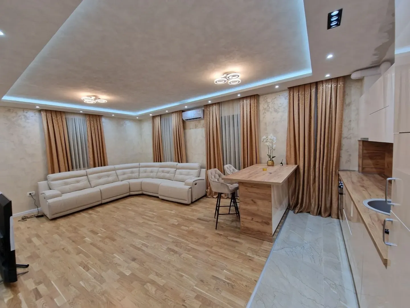 Spacious open-plan living room with a corner sofa and kitchen area.