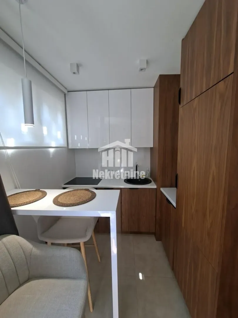 Modern kitchen with white and wooden cabinets and a dining table.