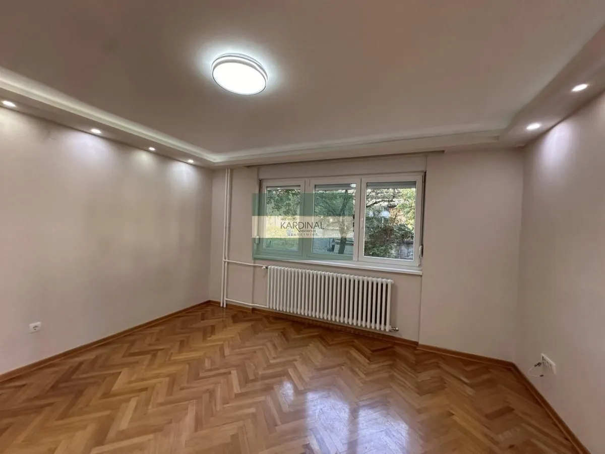 Empty room with parquet flooring and a window.
