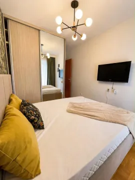 Furnished bedroom with a double bed, mirrored wardrobe, and wall-mounted TV. - image 7
