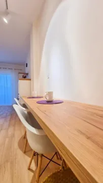 Long wooden counter with white chairs along the wall in the kitchen. - image 11