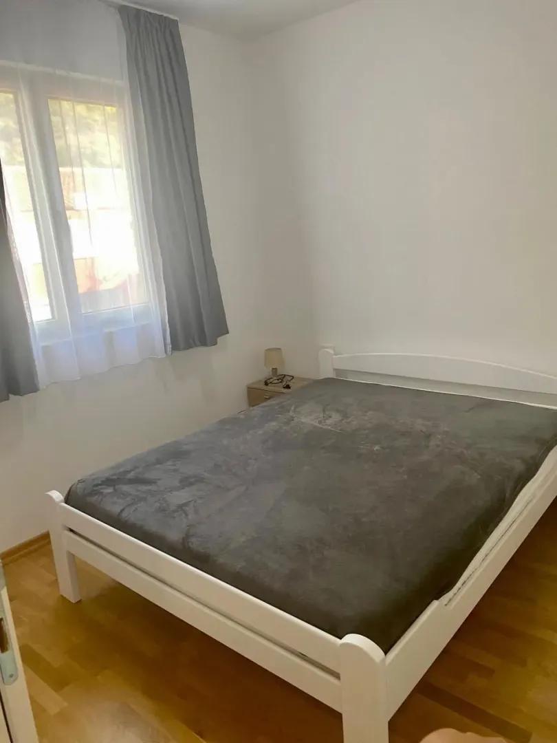 Svjetla spavaća soba sa bijelim krevetom i prozorom.