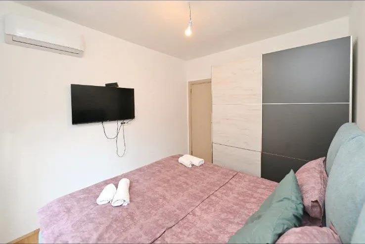 Namještena spavaća soba sa bračnim krevetom, garderoberom, klima-uređajem i televizorom.