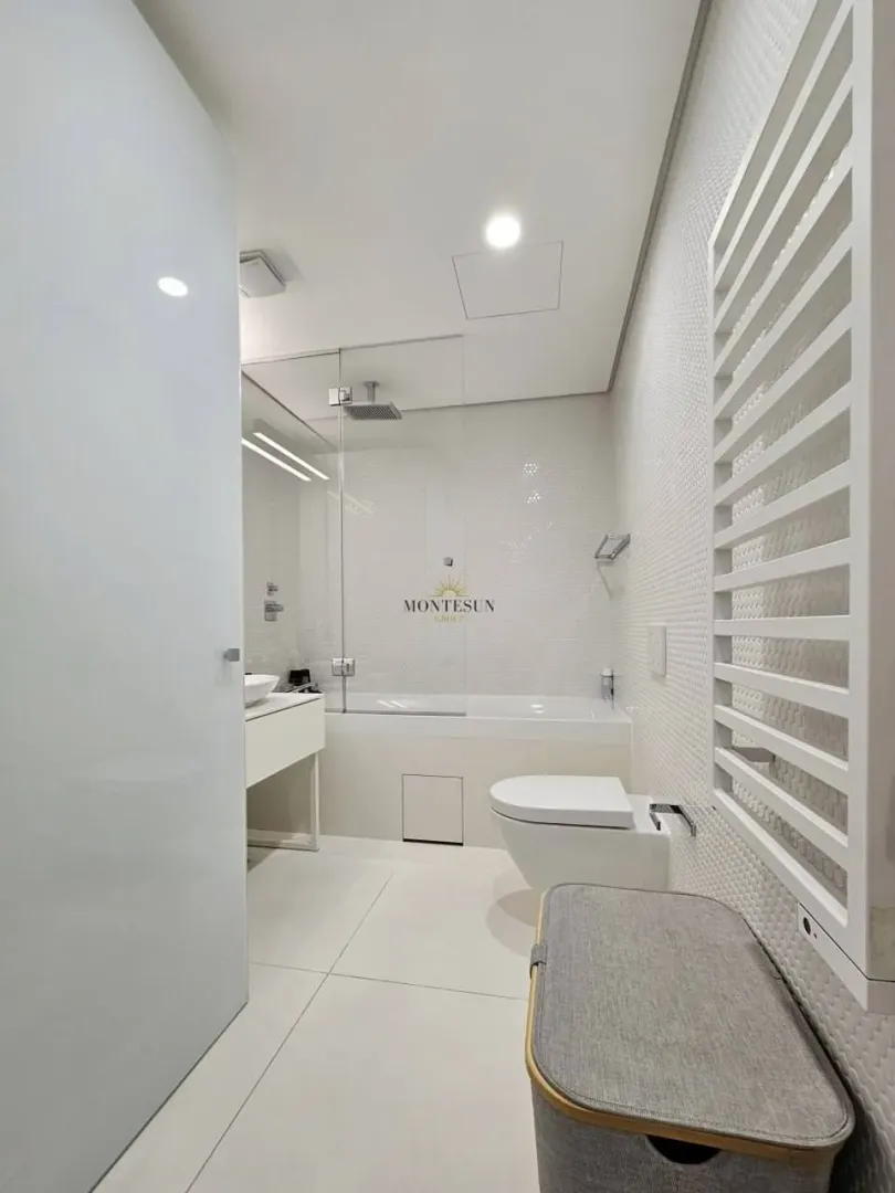 Modernly equipped bathroom with a bathtub and toilet in light tones.
