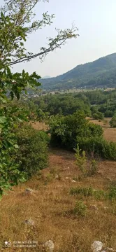Pogled na prostrani plac okružen prirodnim pejzažem i brdima. - image 11