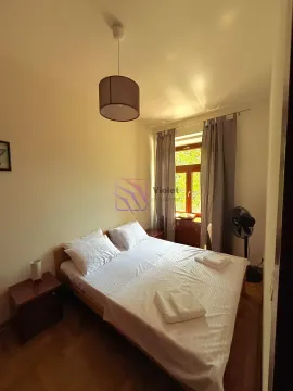 Manja spavaća soba sa bračnim krevetom, noćnim stočićima i prozorom. - image 4