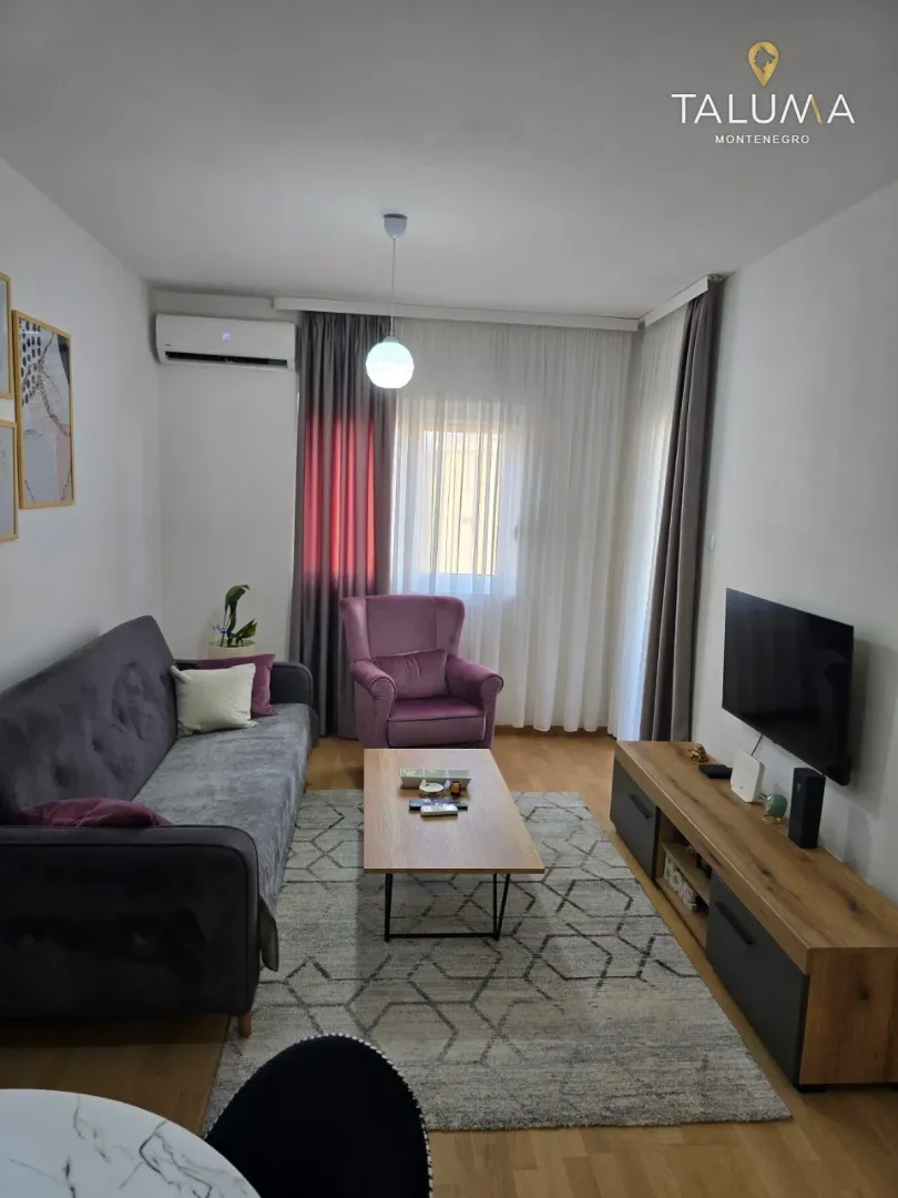 Living room with a sofa, armchair, TV, and dining table.