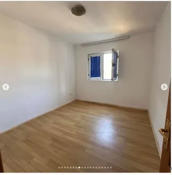 Prazna soba sa svijetlim zidovima, drvenim podom i jednim prozorom. - image 7