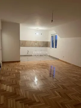 Spacious empty room with parquet flooring and a tiled kitchen area. - image 2