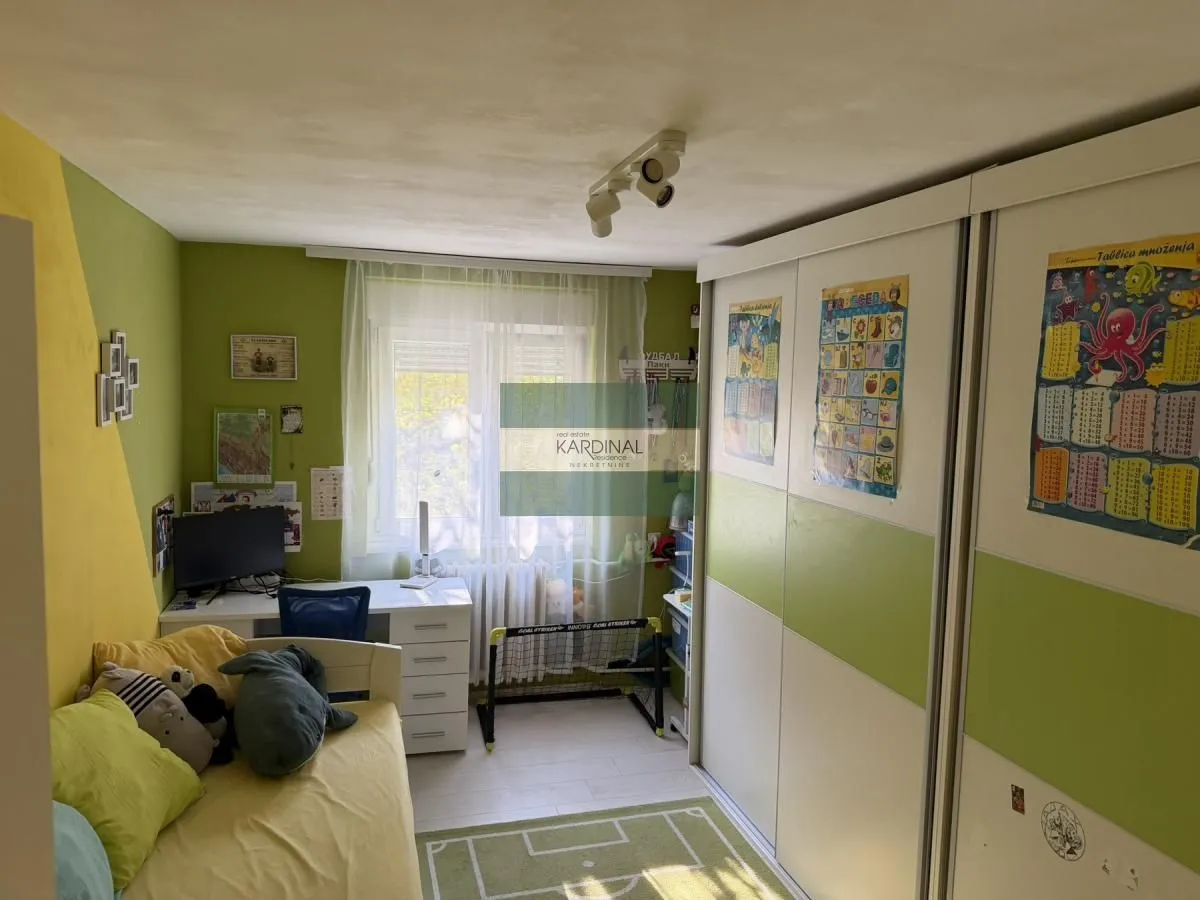 Dečja soba sa krevetom, radnim stolom i velikim ugradnim plakarom.