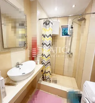 Smaller bathroom with a washbasin, shower cabin, and washing machine. - image 9