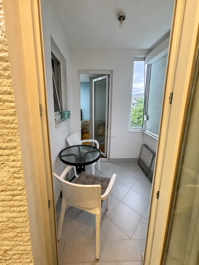 Zastakljeni balkon sa stočićem i dvije stolice.