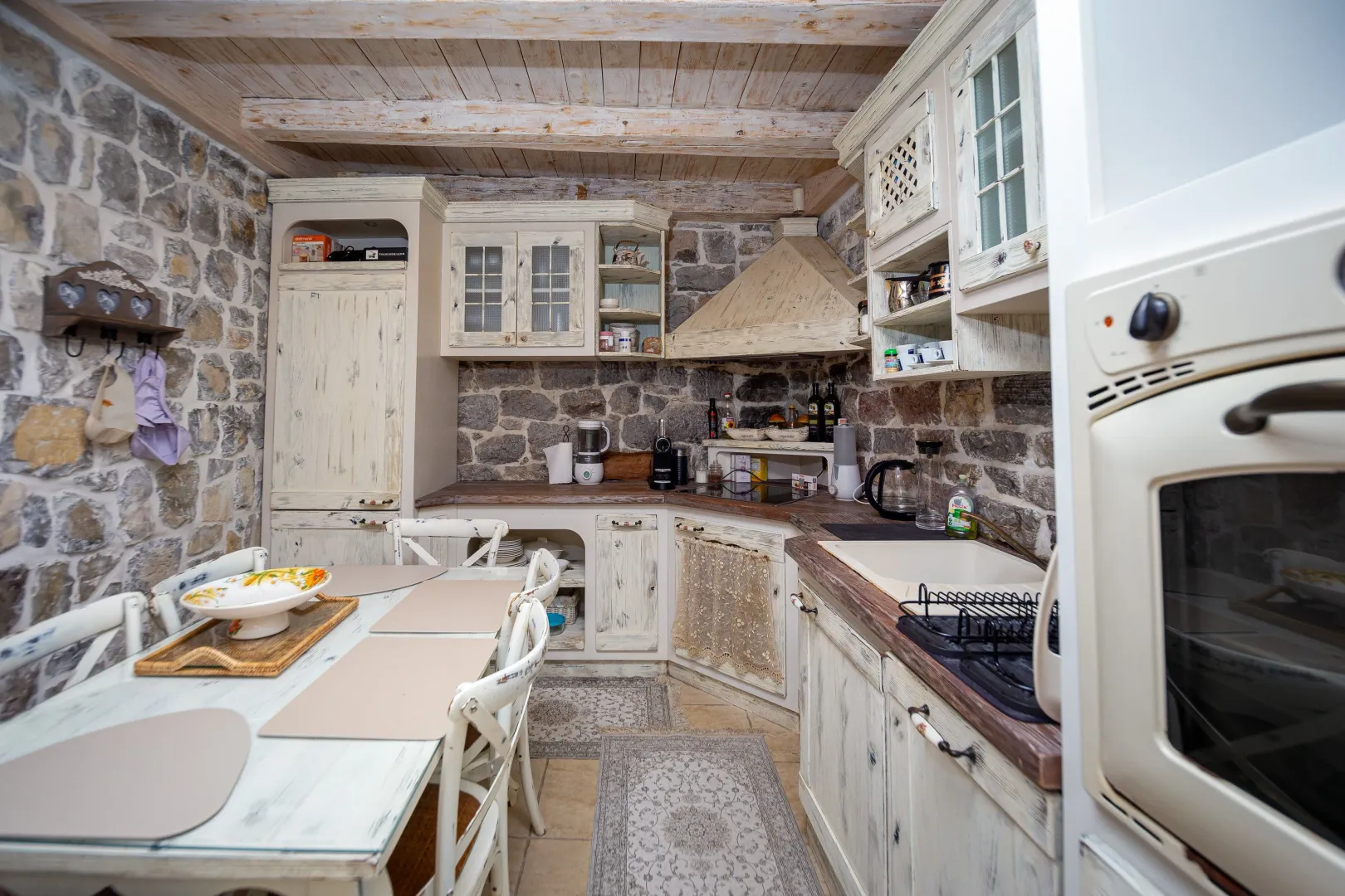 Rustic kitchen with wooden elements, stone walls, and a dining table.