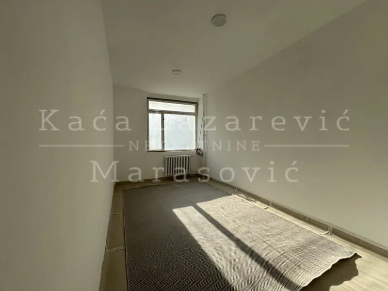Empty room with a window and a large rug on the floor.