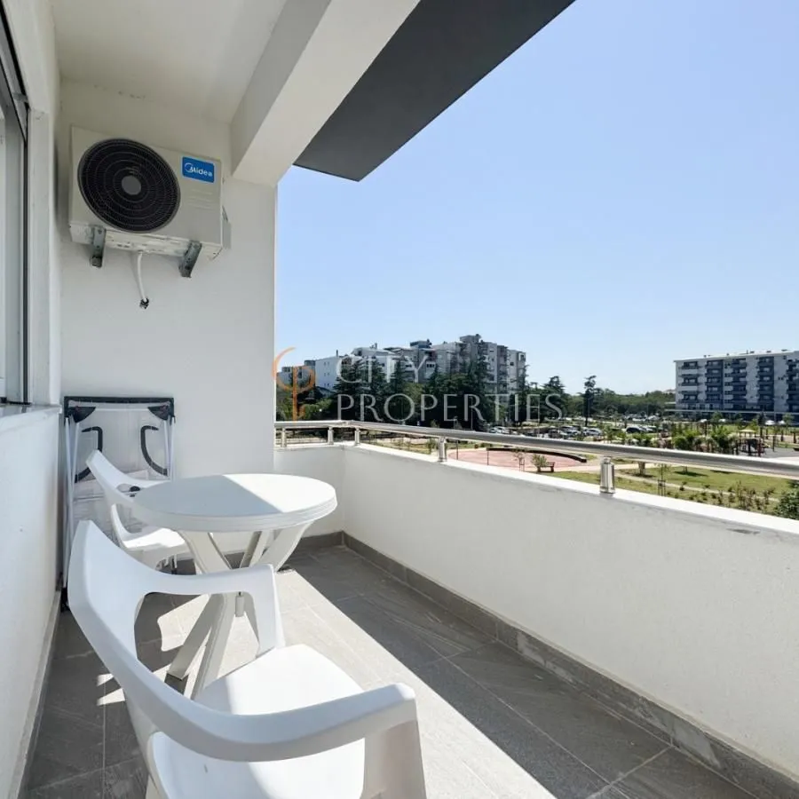 Manji namješteni balkon sa stolom, stolicama i klima uređajem.