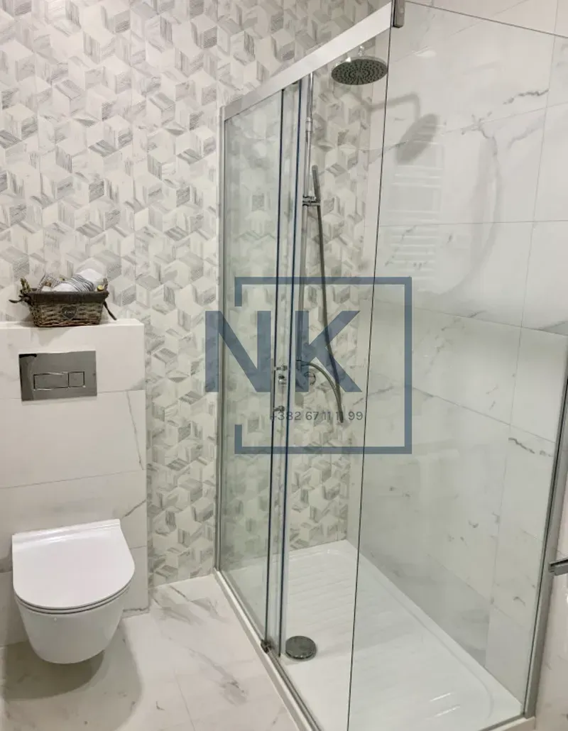 Moderno opremljeno kupatilo sa tuš kabinom i ugradnom šoljom.