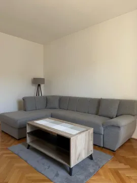 Living room with a sectional sofa, coffee table, and lamp. - image 2