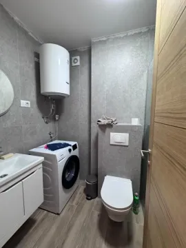 Bathroom equipped with a shower cabin, washbasin, toilet, water heater, and washing machine. - image 7