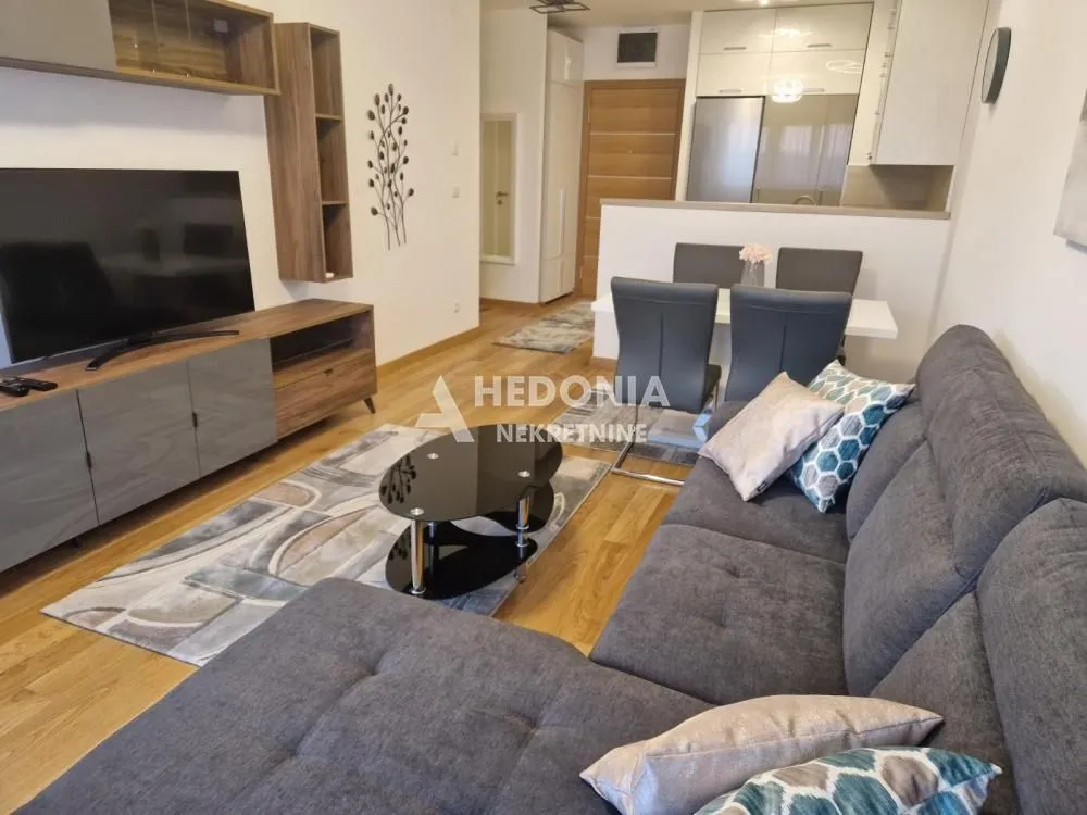 Living room with a sofa, TV, and a dining area in the background.