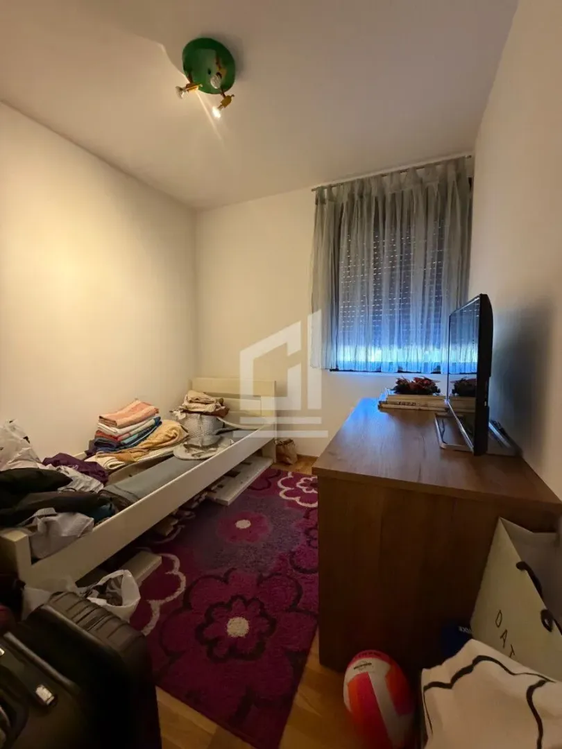 Manja spavaća soba sa krevetom, radnim stolom i televizorom.