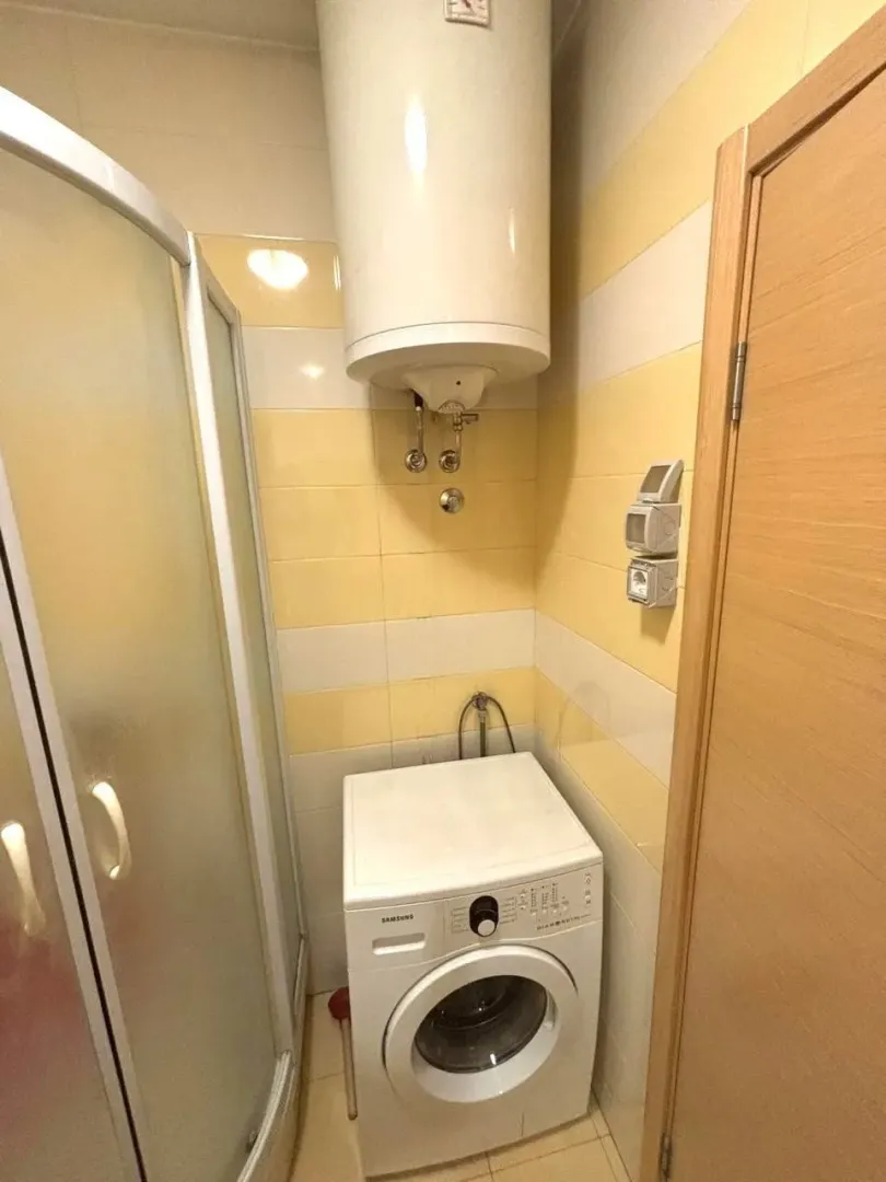 Bathroom with a shower cabin, water heater, and washing machine.
