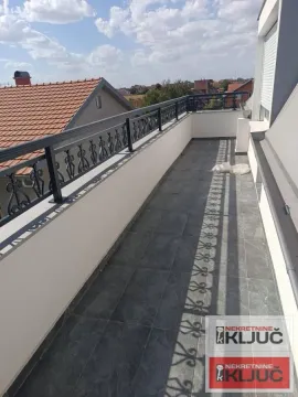 Prostrani popločani balkon sa metalnom ogradom i pogledom na naselje. - image 11