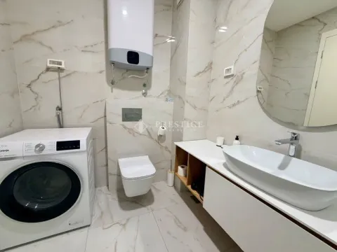 Modern bathroom with a washbasin, toilet, water heater, and washing machine. - image 12
