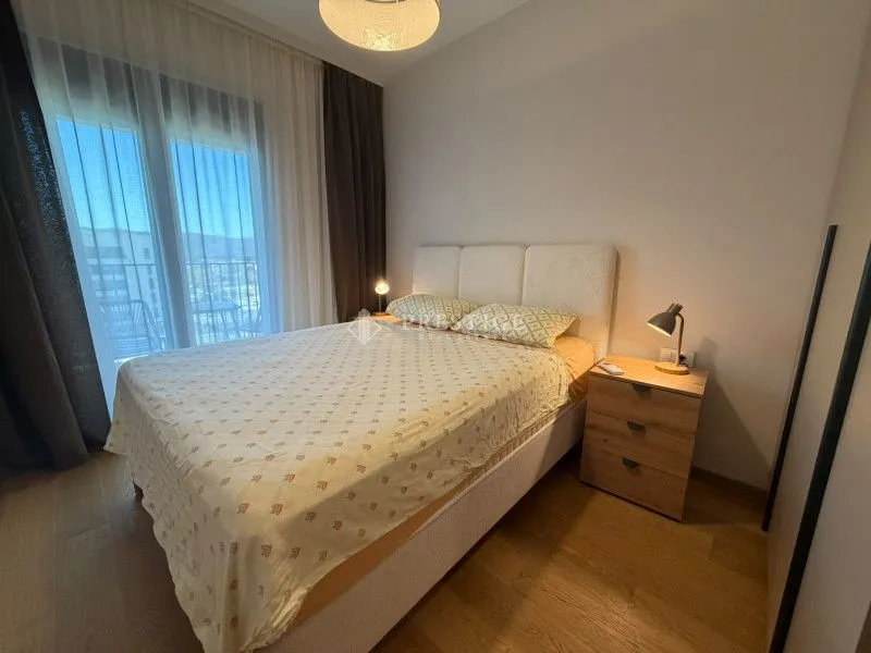 Namještena spavaća soba sa bračnim krevetom i noćnim stočićem.