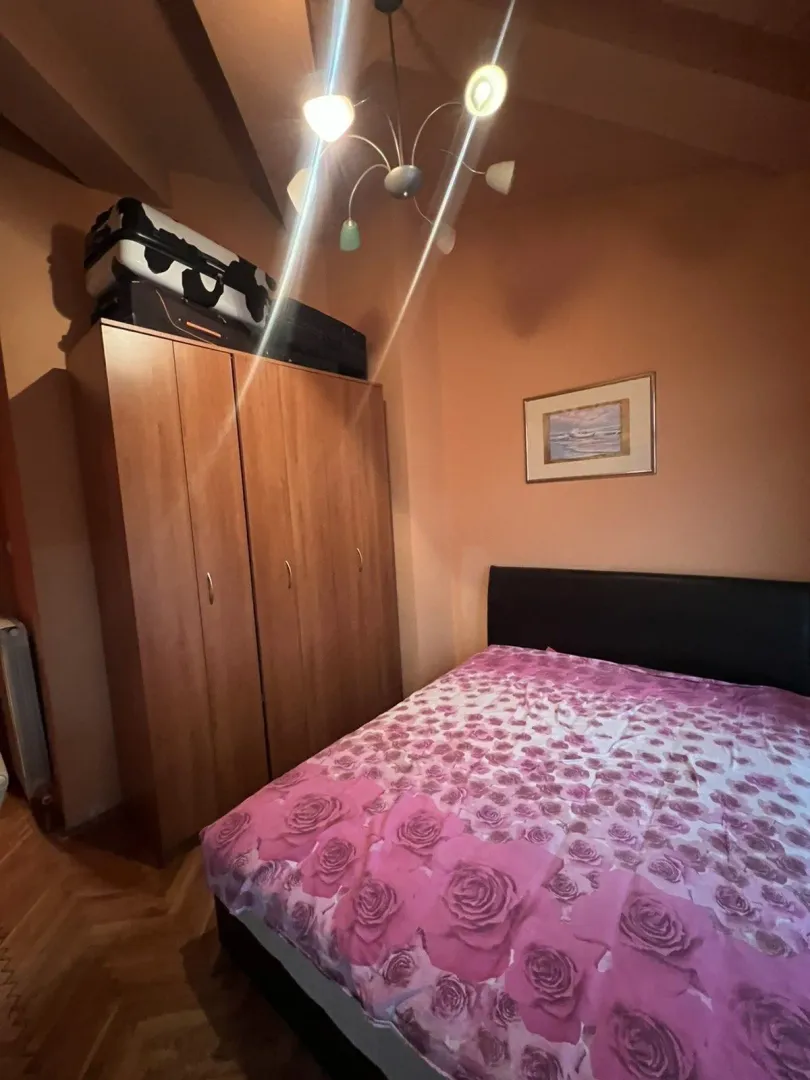 Jednostavna spavaća soba sa bračnim krevetom i drvenim ormarom.
