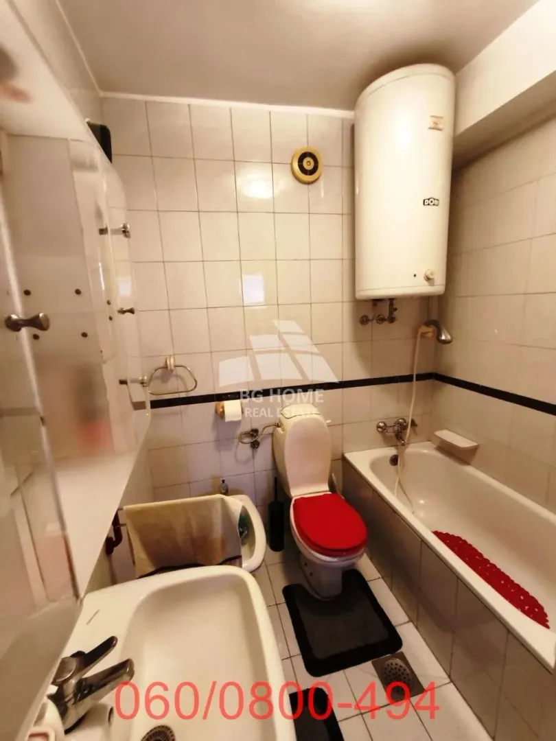Manje kupatilo sa kadom, wc šoljom, bideom i bojlerom na zidu.