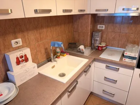 Smaller kitchen with a sink, countertop, and white cabinets. - image 6