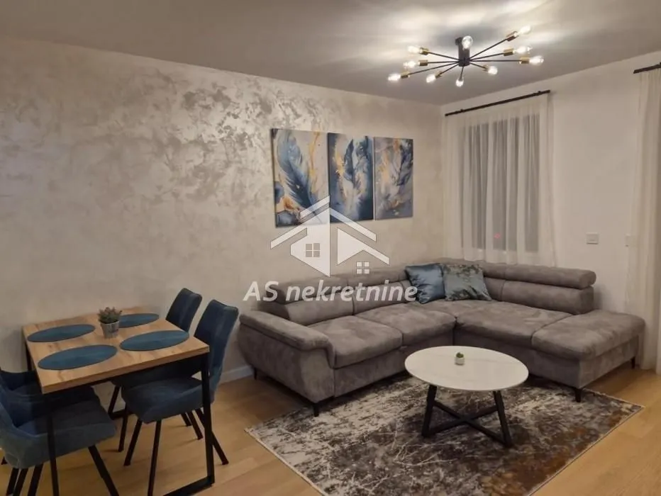 Living room with a sofa, dining table, and decorative wall.