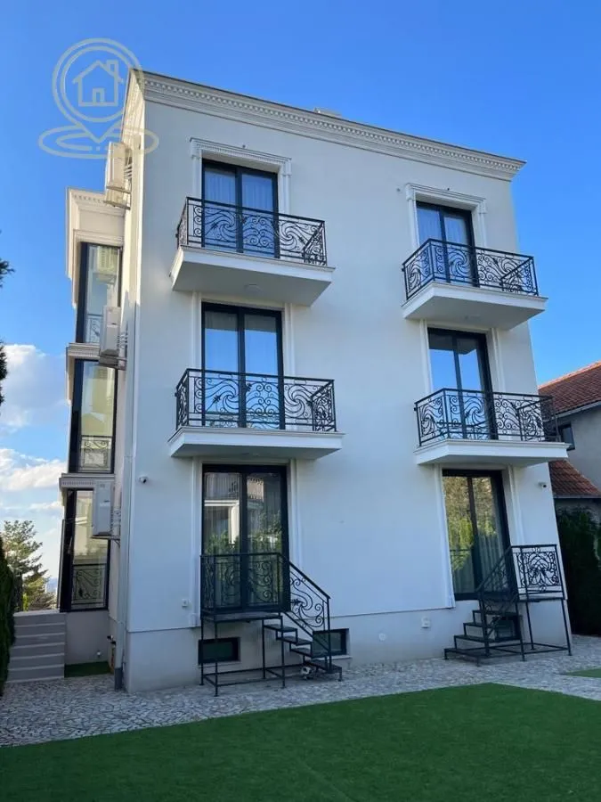 Pogled na zadnju fasadu višestpratne zgrade sa balkonima i travnjakom u dvorištu.