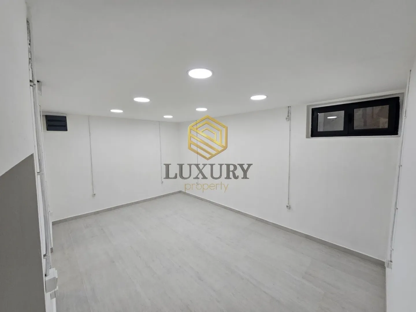 Empty bright room with white walls and recessed lighting.