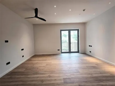 Prazna soba sa drvenim podom, plafonskim ventilatorom i balkonskim vratima. - image 2